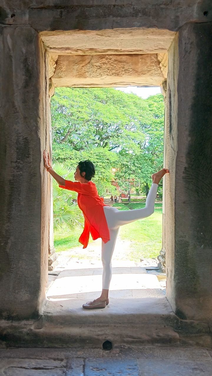 Elizabeth in a standing yoga pose in a stone doorway